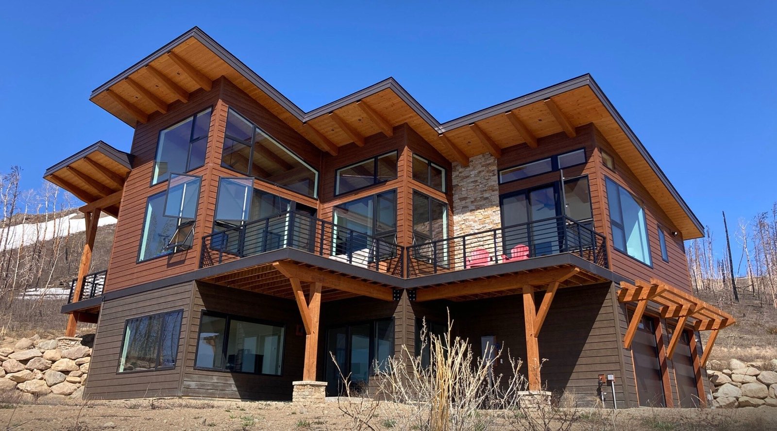 Two-storey timber and stone mountain home with floor-to-ceiling windows framing Sierra Nevada, Bear Valley California