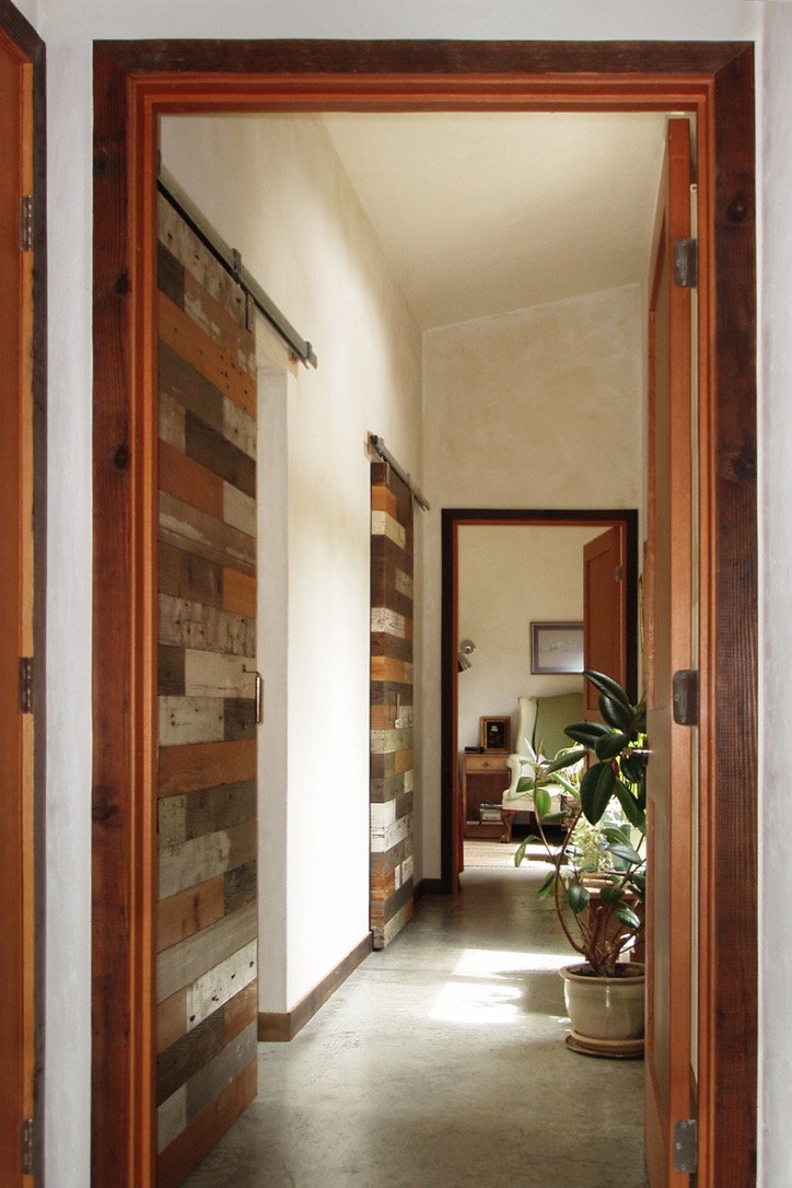 Reclaimed wood sliding barn door with lime plaster hallway — bespoke carpentry and joinery